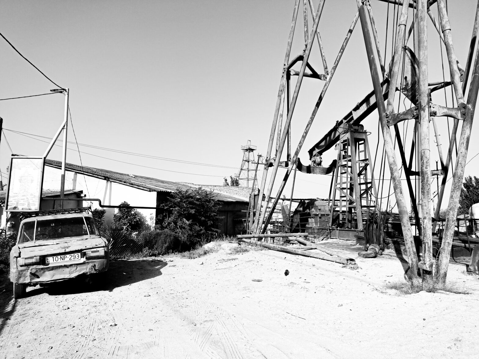 A Soviet-Era Lada next to a complex of oil rigs. Ⓒ Oliver Banks, 2022.